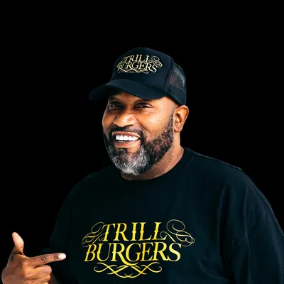 Bun B pointing at the Trill Burgers logo on his shirt